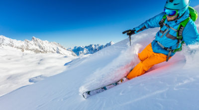 Freerider skier running downhill in beautiful Alpine landscape. Fresh powder snow, blue sky on background.
